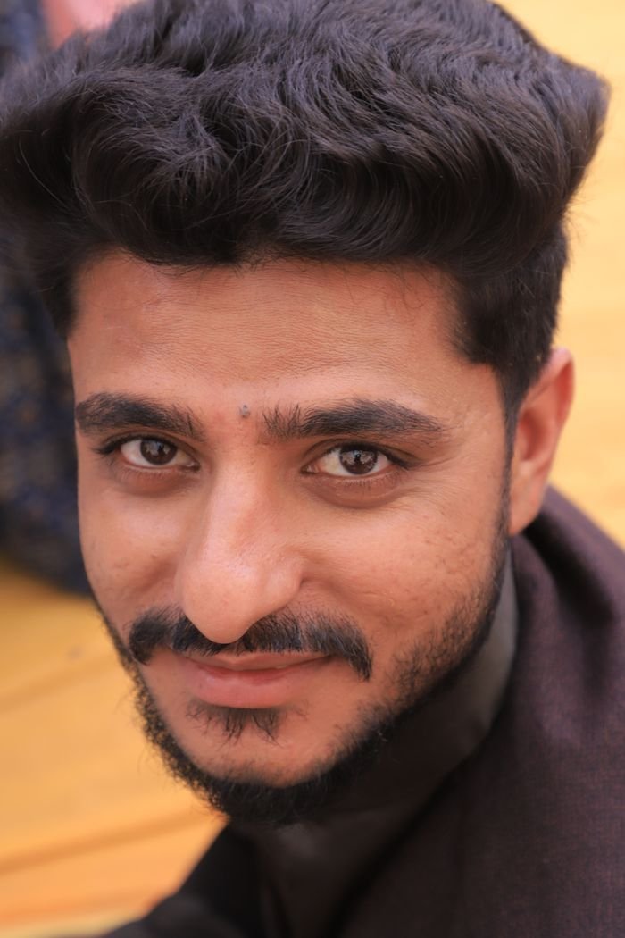 Close-up portrait of a smiling man with facial hair in Dhari, Gujarat, India.