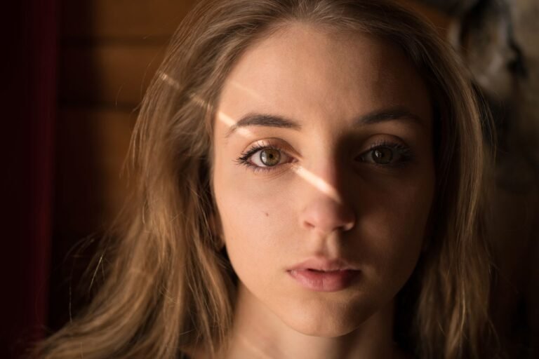 Captivating close-up portrait of a young woman with natural lighting creating a dramatic effect.